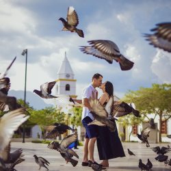 A romantic couple kissing amidst flying pigeons in Valledupar, Colombia.
